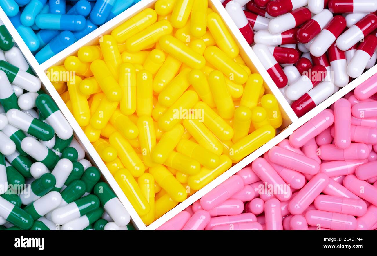 Top view colorful capsule pills in a plastic tray. Yellow, pink, red