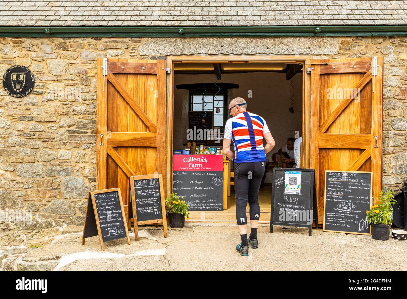 A cyclist wearing a union flag summer shirt, stops for a break at a well known cafe eatery close to St Agnes Cornwall England UK Stock Photo