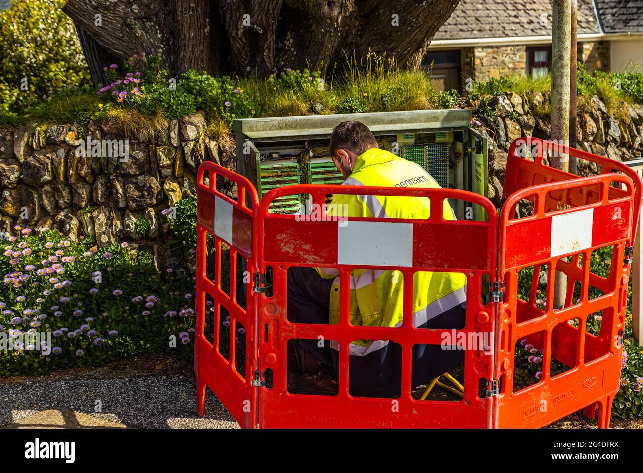A telecoms engineer works on solving connection issues in a street cabinet, Cornwall England UK Stock Photo