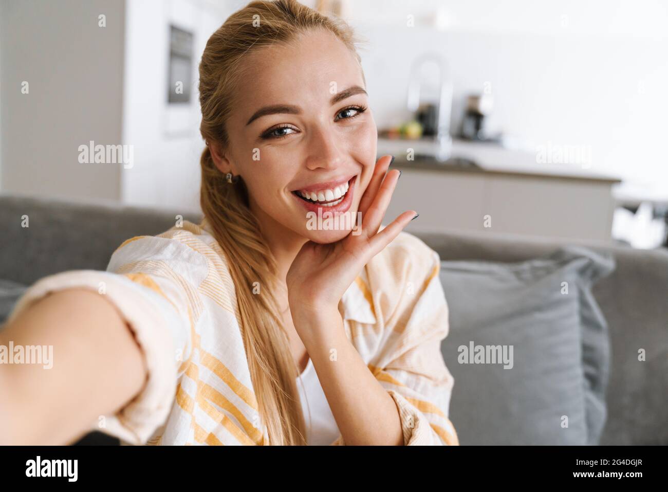 Happy blonde woman smiling while taking selfie photo at home Stock ...