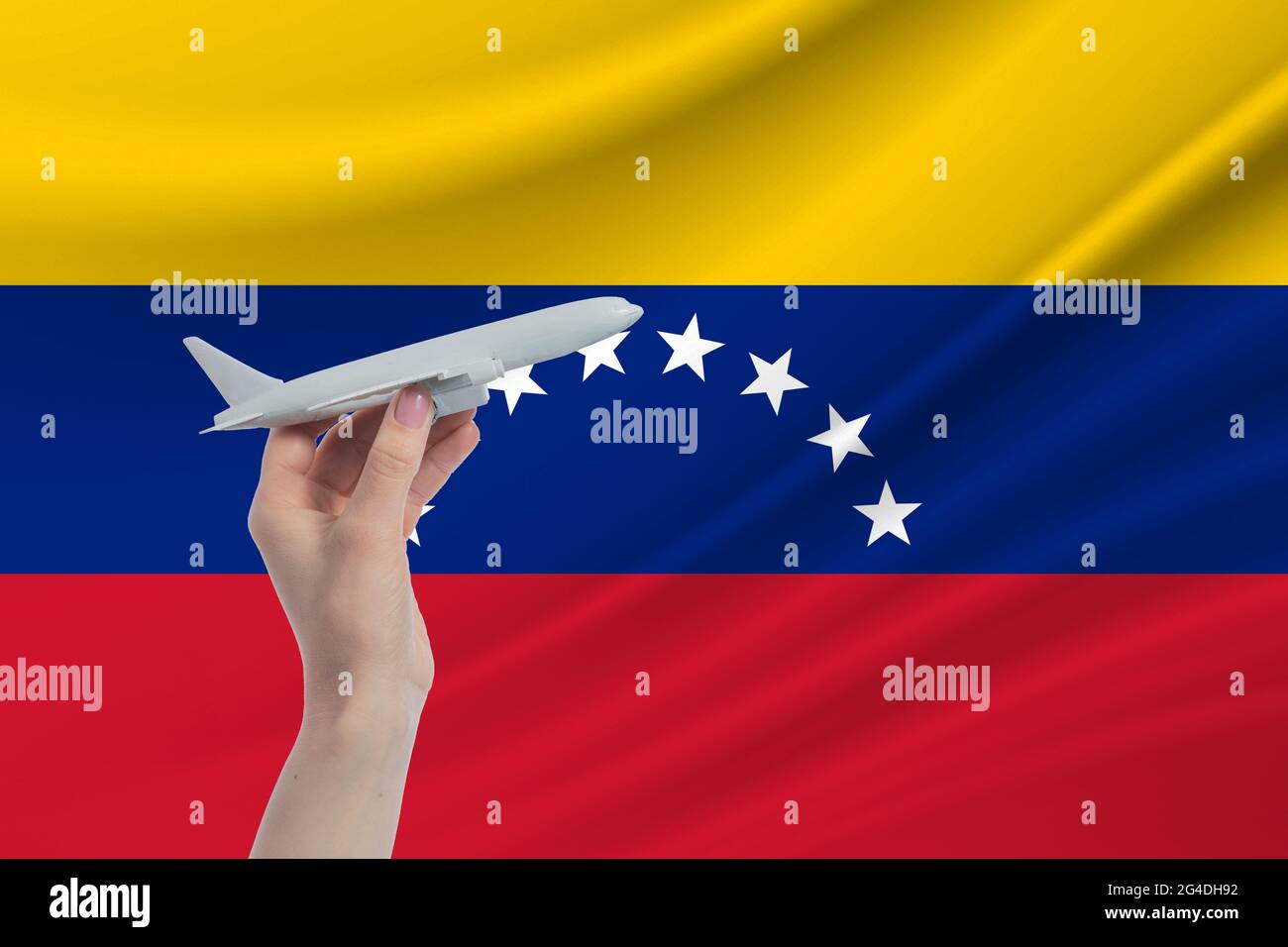 Airplane in hand with national flag of Venezuela. Travel to Venezuela. Stock Photo