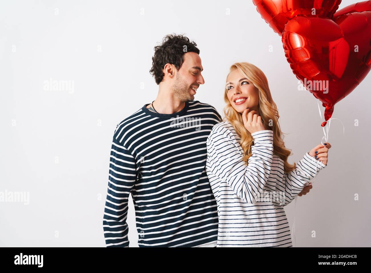 Happy romantic couple smiling while posing with heart balloons isolated ...