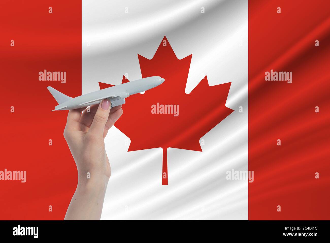 Airplane in hand with national flag of Canada Travel to Canada. Stock Photo
