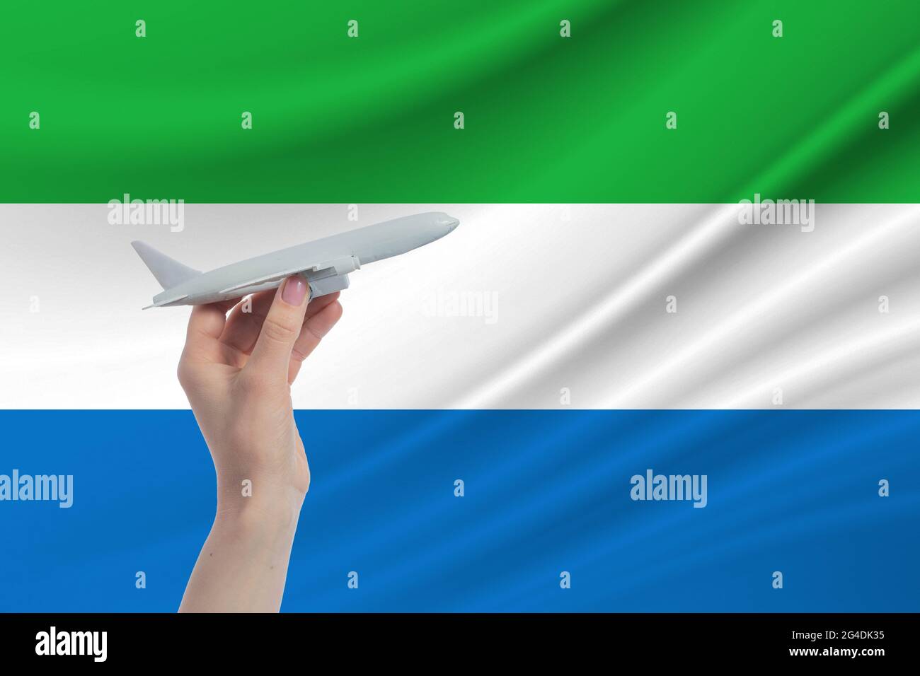 Airplane in hand with national flag of Sierra Leone. Travel to Sierra