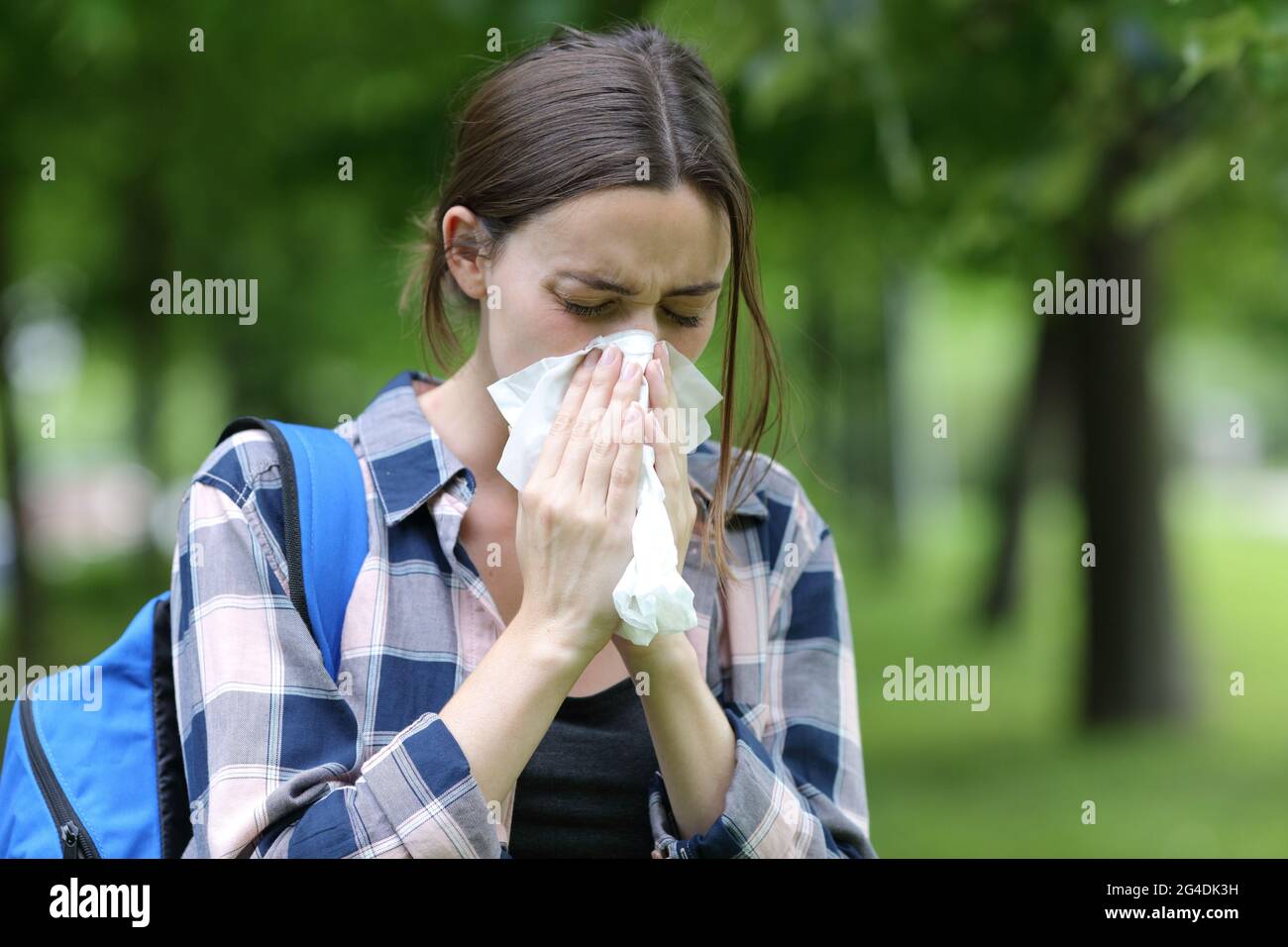Student blowing on tissue on summer in a park or campus Stock Photo