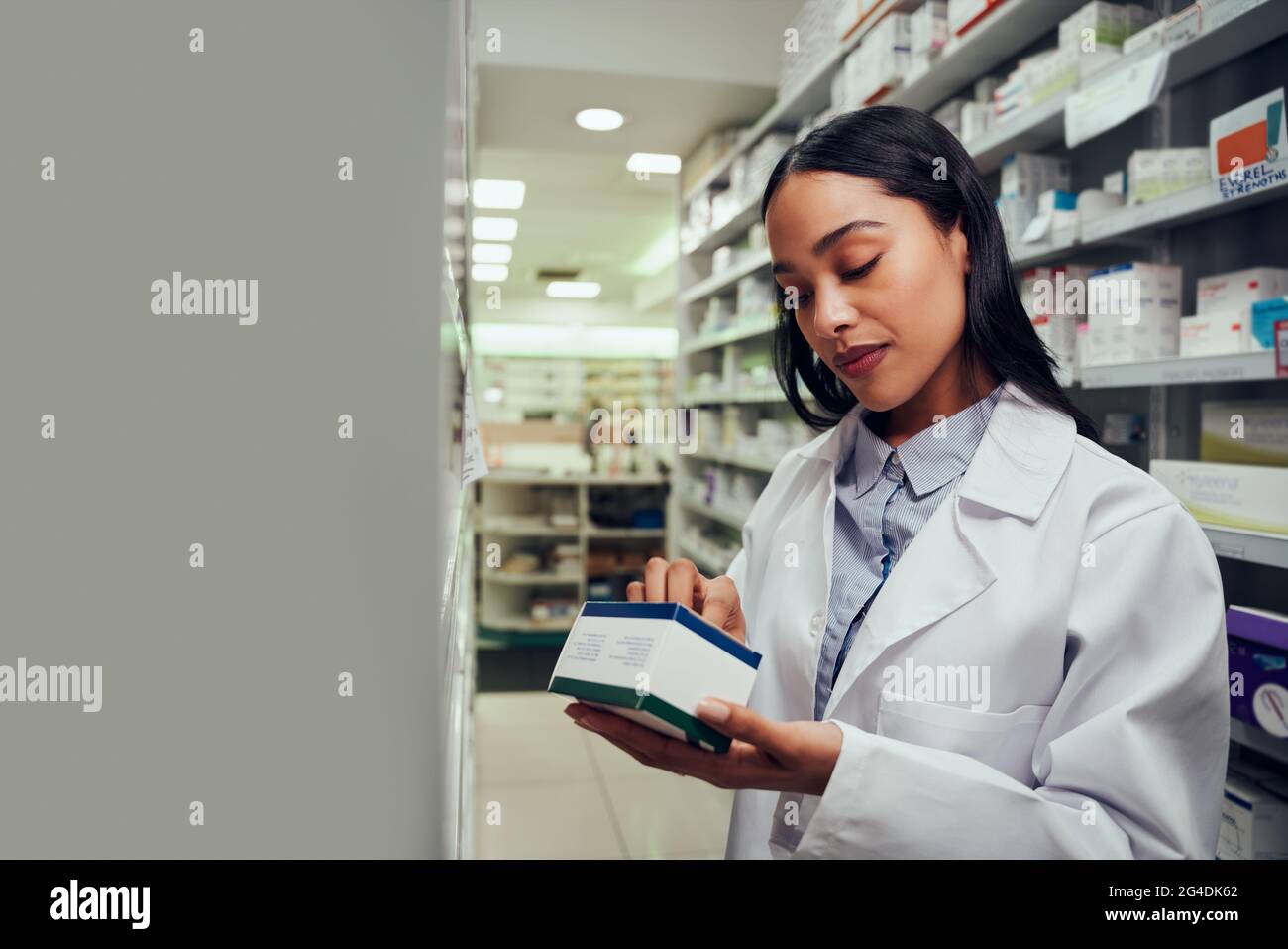 Woman checking medicine box reading expiry date and instructions standing in aisle of chemist Stock Photo