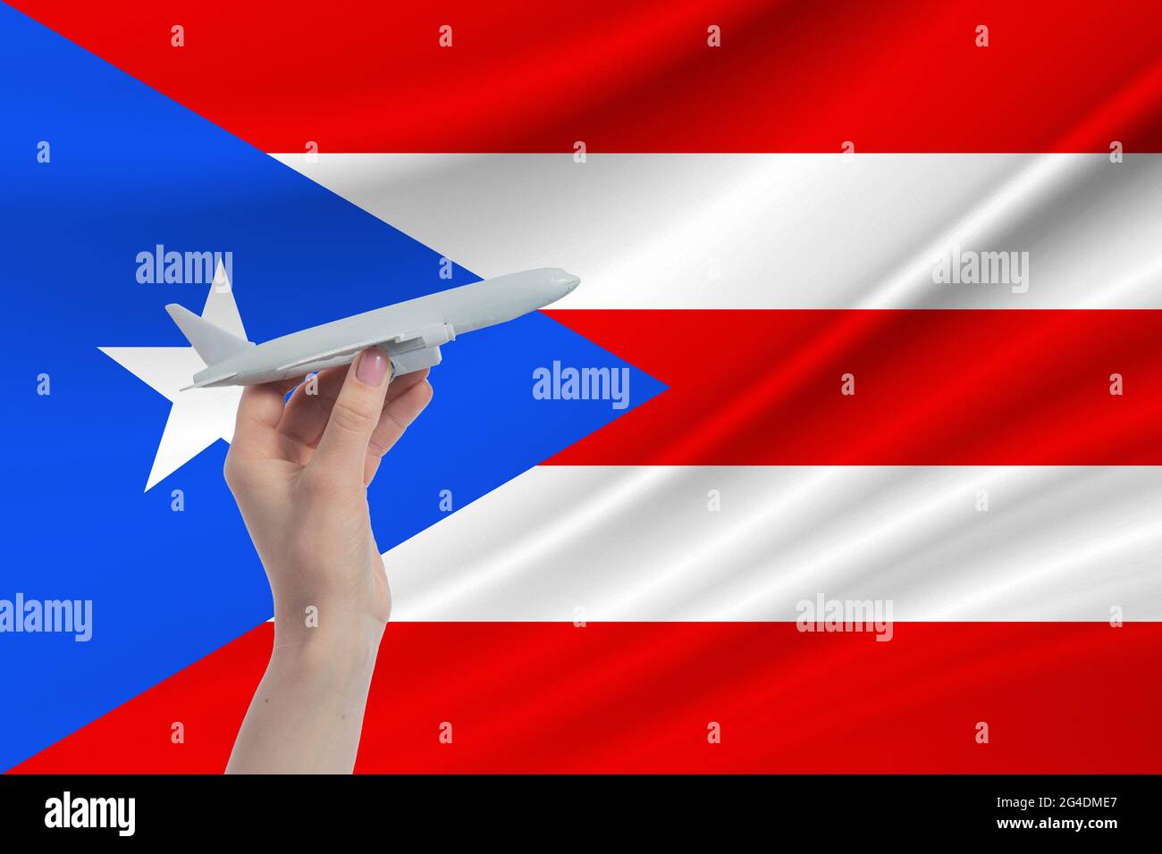Airplane in hand with national flag of Puerto Rico. Travel to Puerto