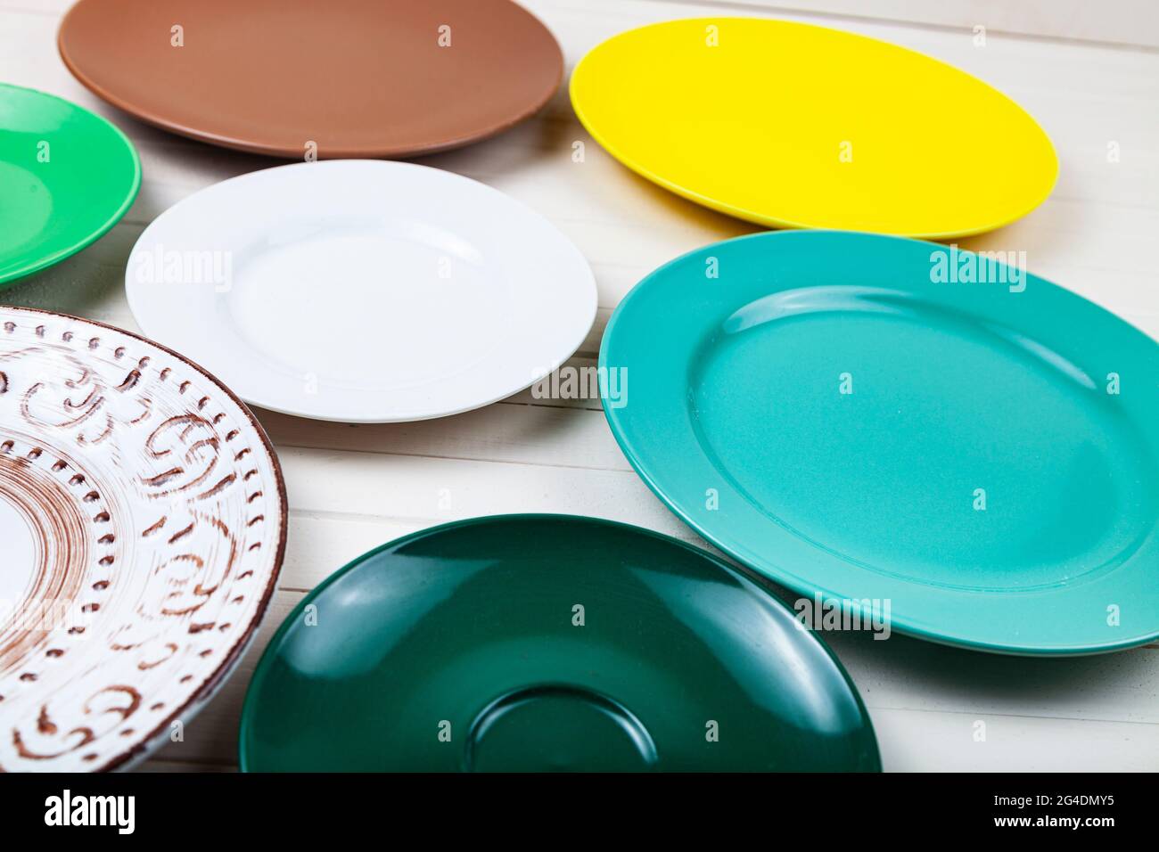 Empty multicolored plates on a wooden background, top view. Stock Photo