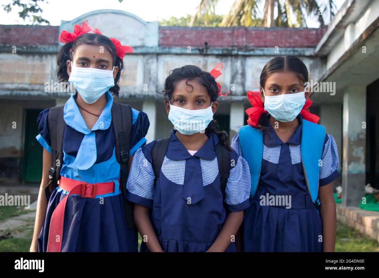 Three indian Rural School Girl wearing Mask Standing in school Stock Photo