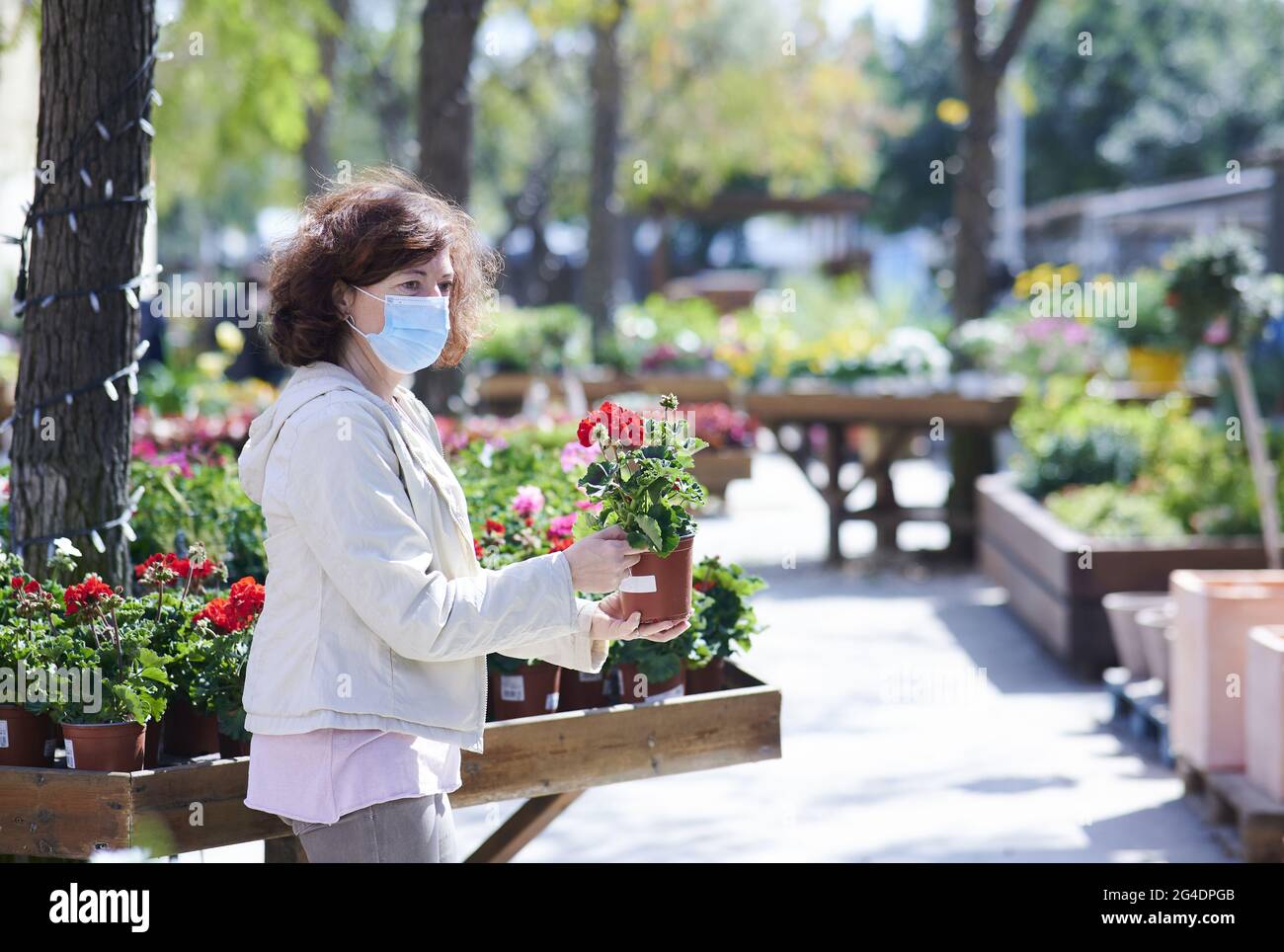Spanish Caucasian woman picking a flower pot in an outdoor flower