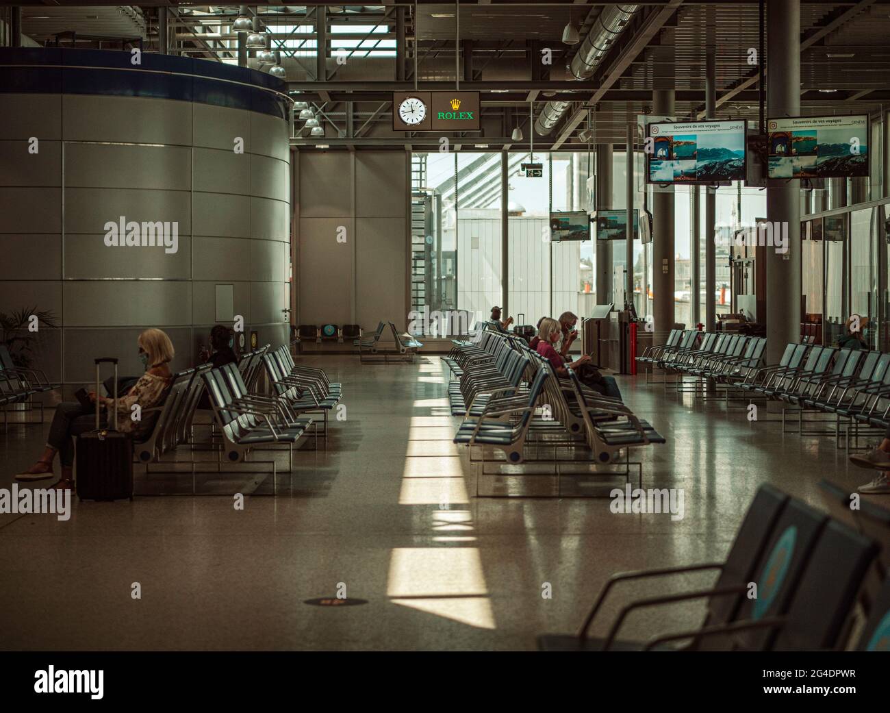 Passengers queue in a airport departure lounge. The passengers all wearing masks queue in an airport departure lounge at Geneva airport. Stock Photo