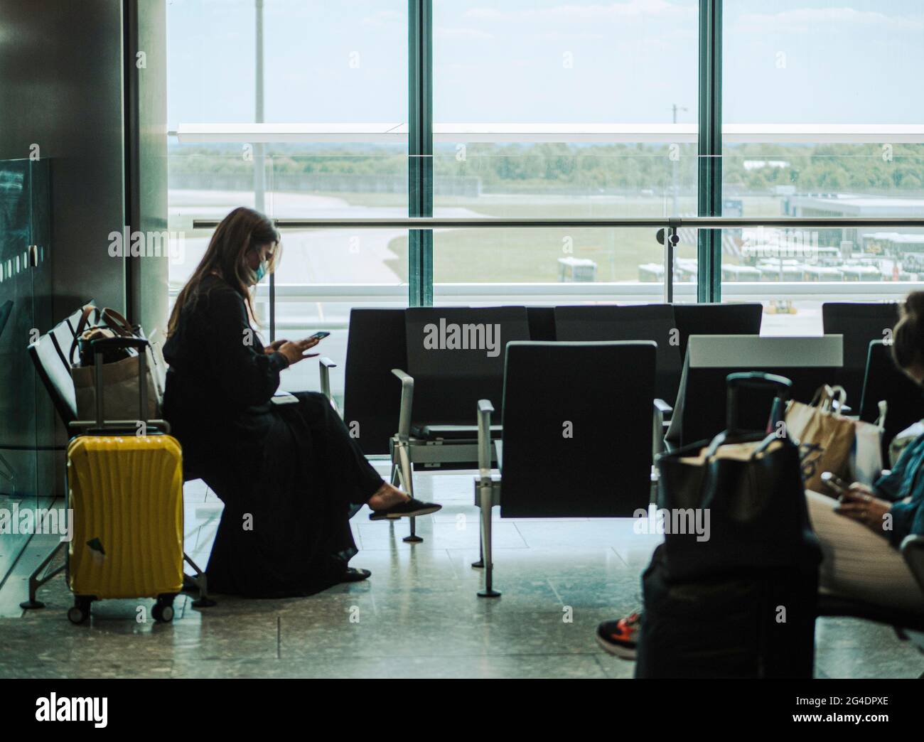 Passengers queue in a airport departure lounge. The passengers all