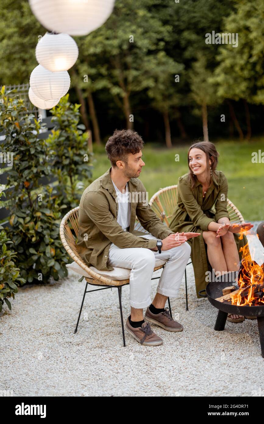Friends sitting by a fireplace at backyard Stock Photo