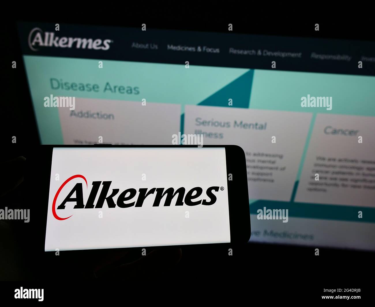 Person holding cellphone with logo of Irish biopharmaceutical company Alkermes plc on screen in front of business webpage. Focus on phone display. Stock Photo