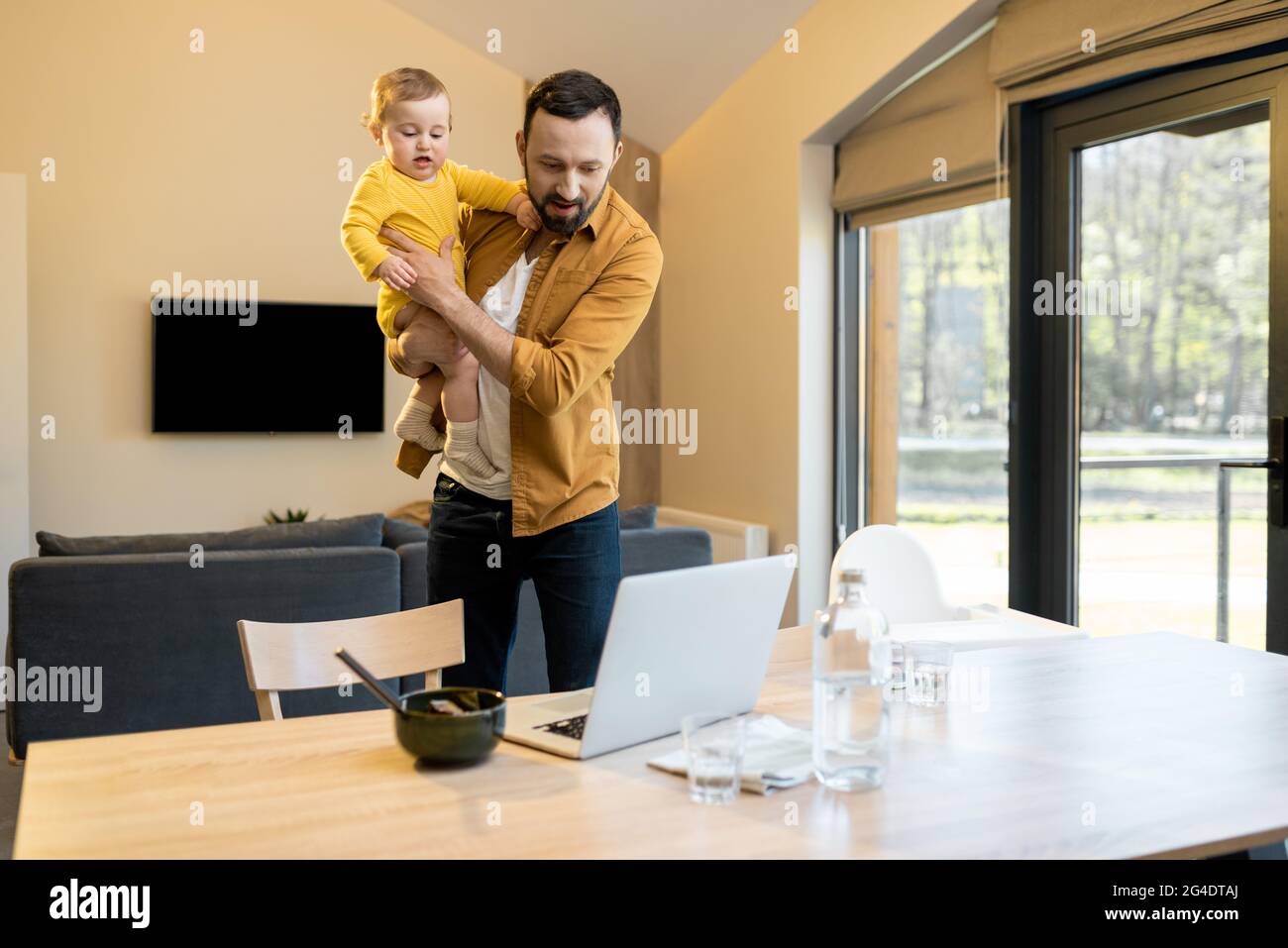 Father nursing his baby son and works from home Stock Photo