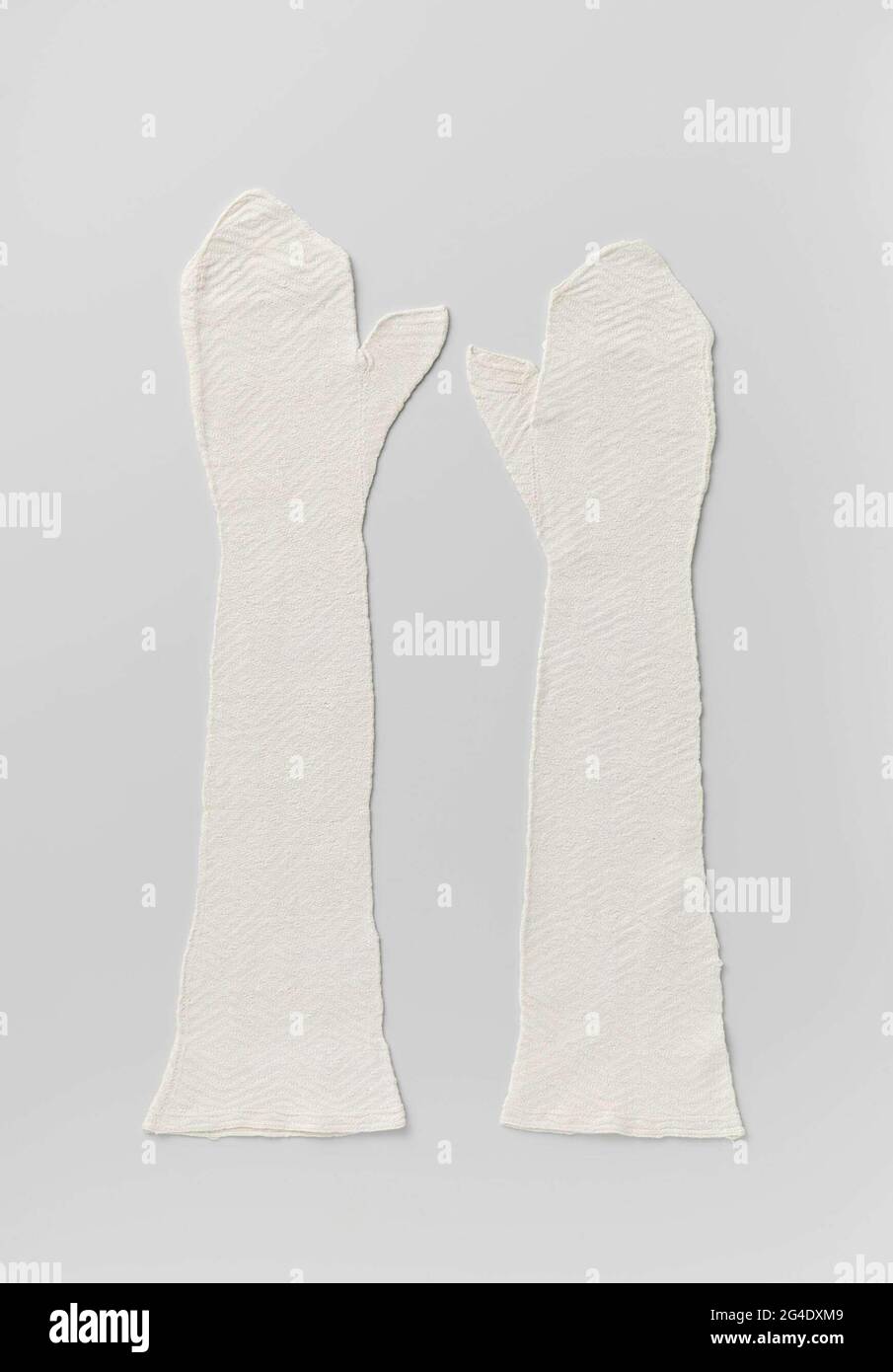 . Mitaine of white knitted cotton with pattern in staggered windows and separately ached thumb. Stock Photo