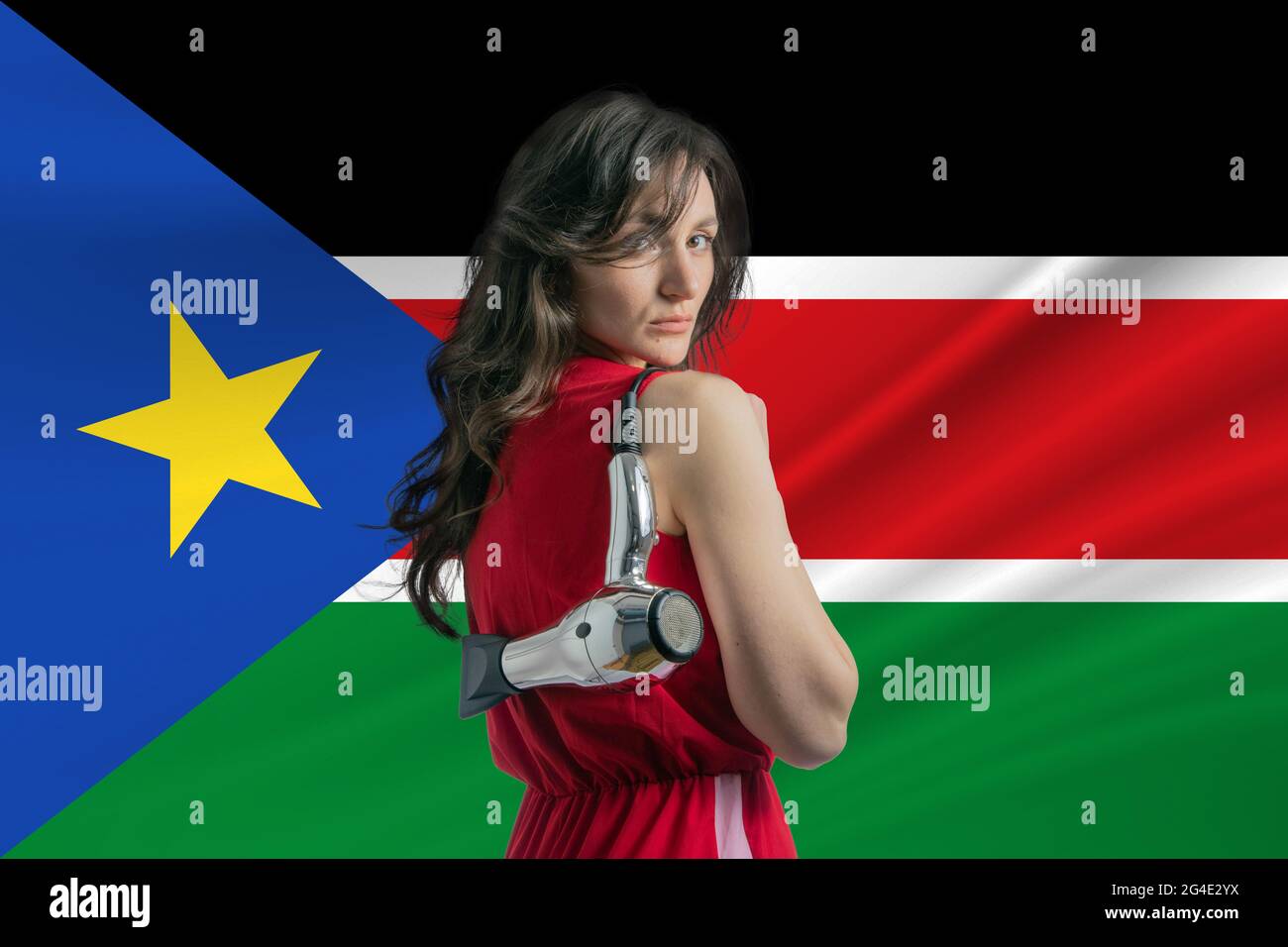 Beauty industry in South Sudan. Happy female hairdresser holding hairdryer against South Sudan flag background. Stock Photo