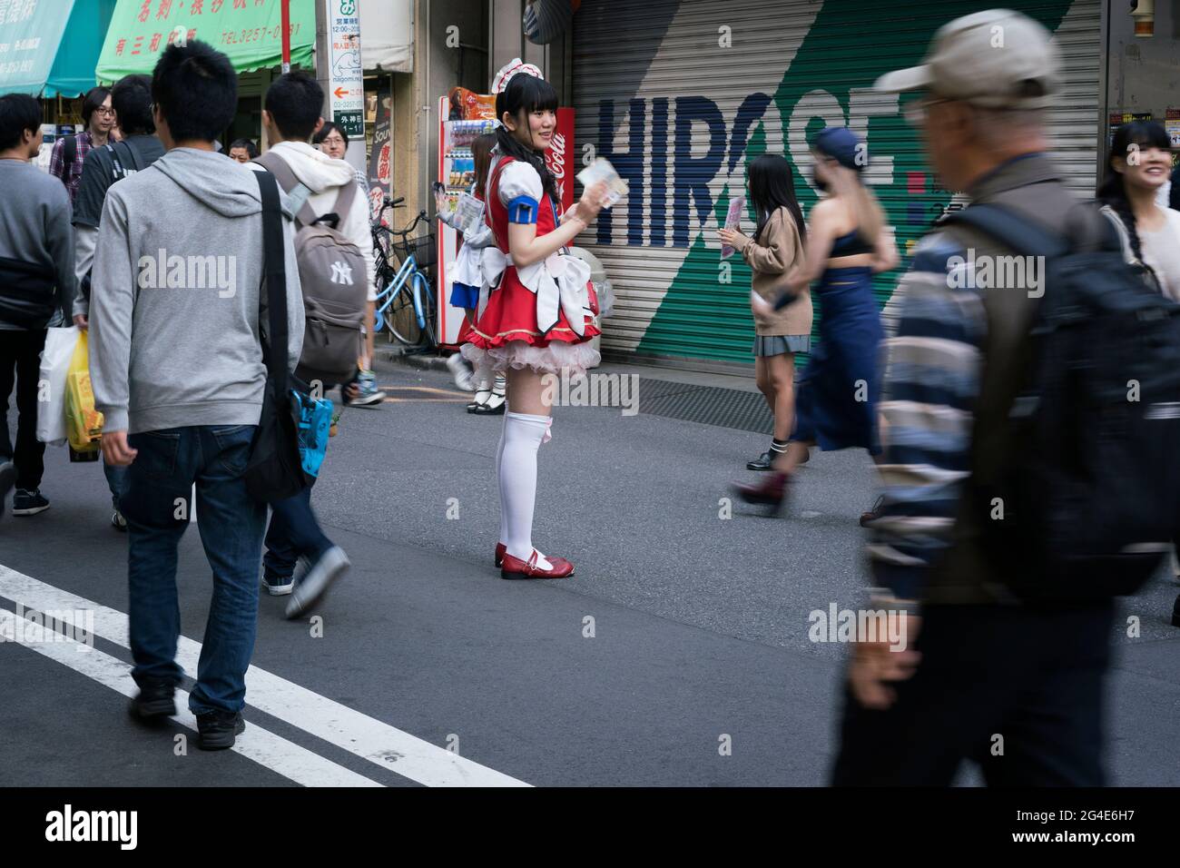 A girl in a maid's costume handing out flyers for a maid cafe on the ...