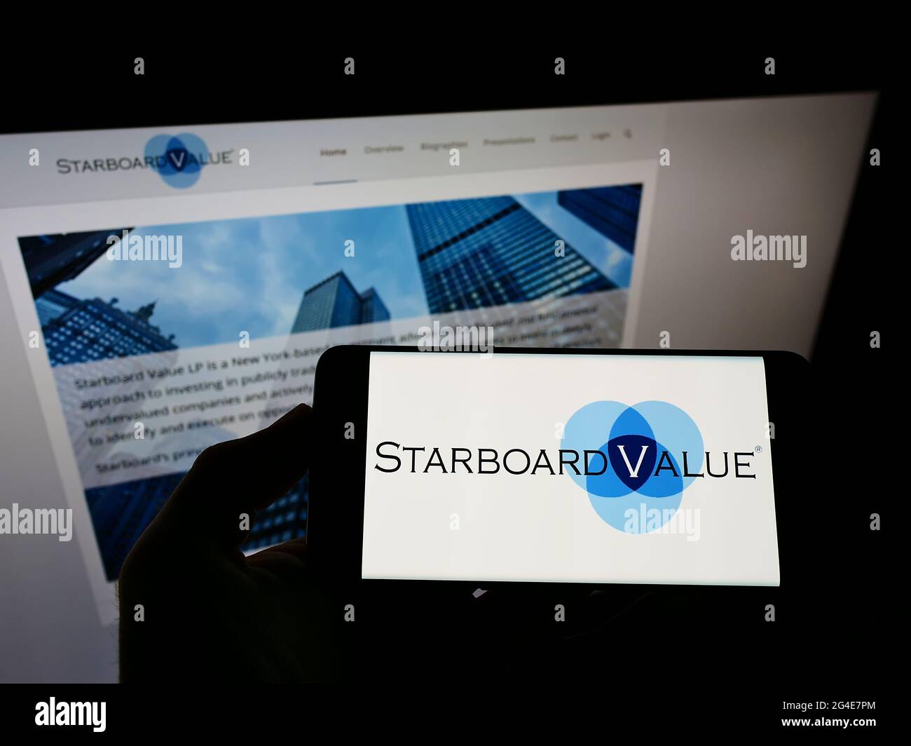 Person holding smartphone with logo of US hedge fund Starboard Value LP on screen in front of website. Focus on phone display. Stock Photo