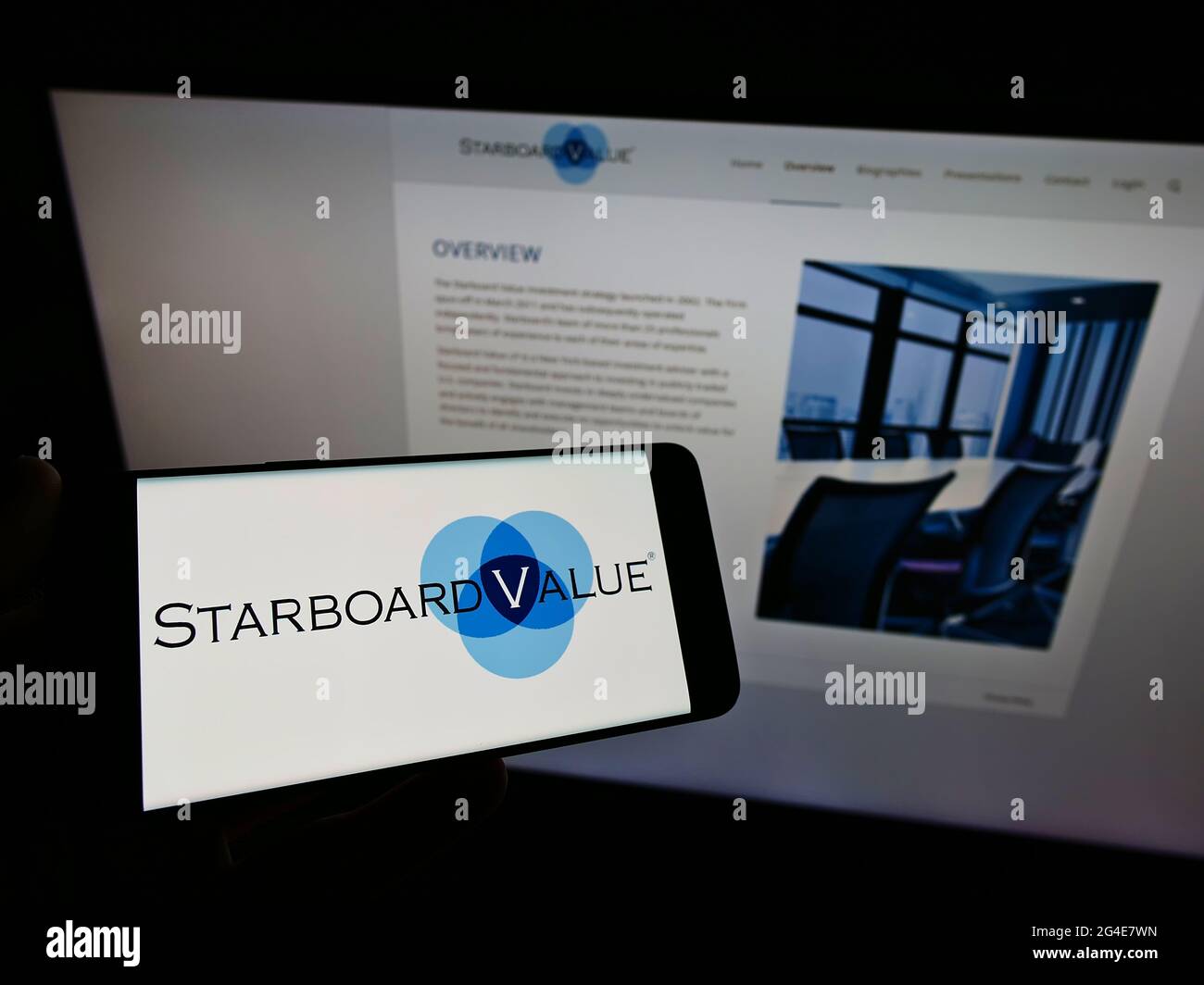 Person holding cellphone with logo of US hedge fund Starboard Value LP on screen in front of business webpage. Focus on phone display. Stock Photo