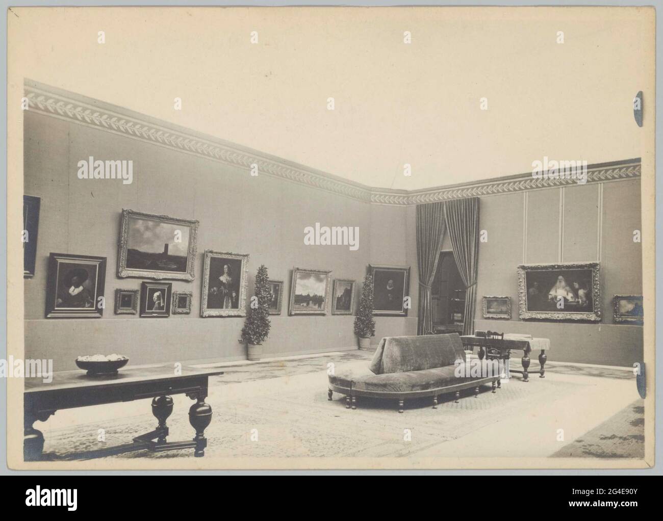 Room with paintings, furniture and curtains next to a passage