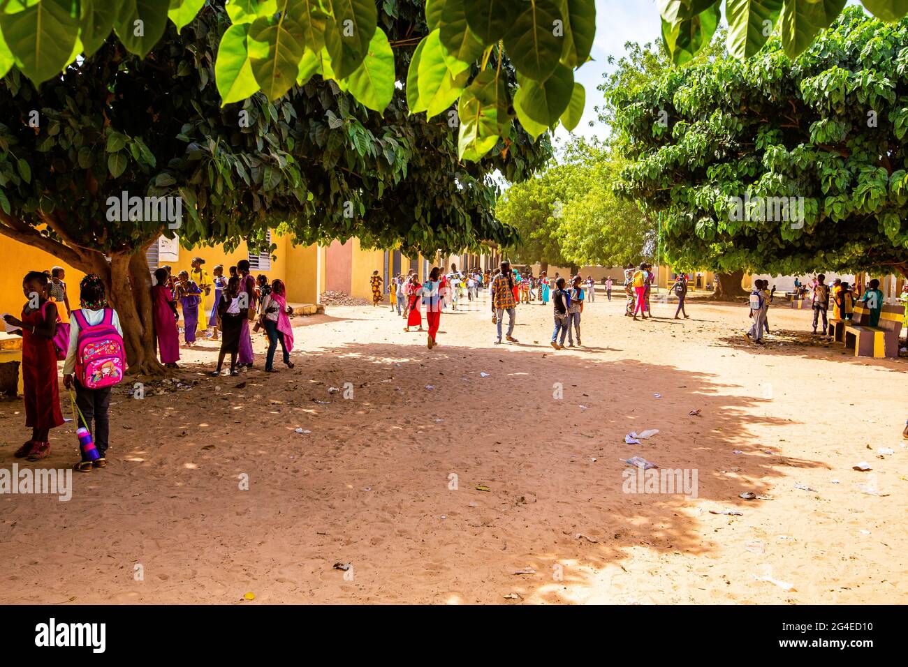 MBOUR, SENEGAL - DECEMBER Circa, 2020. Unidentified young African school children walking in the playground at end of classroom. With colorful clothes Stock Photo