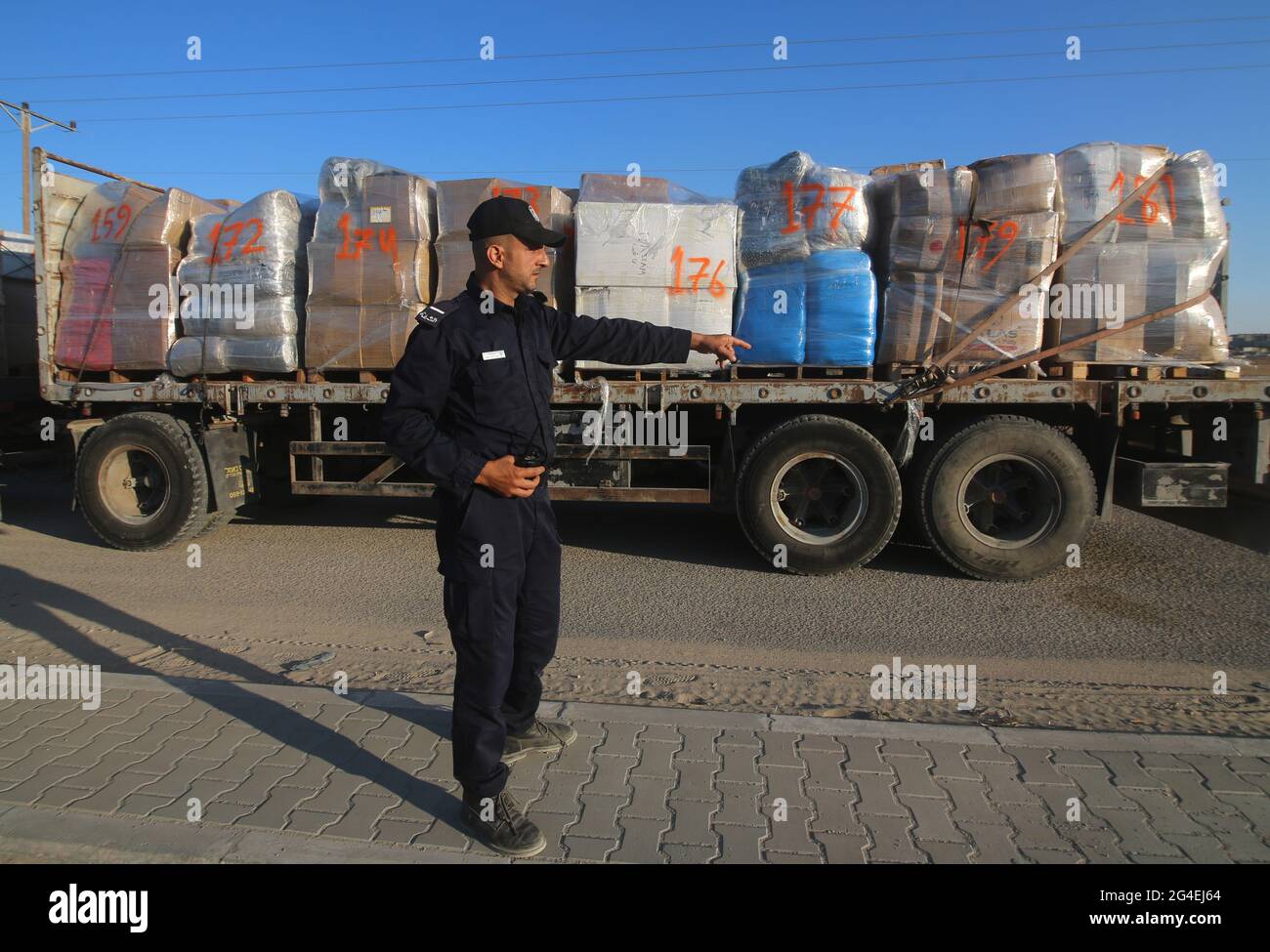 (210621) -- RAFAH, June 21, 2021 (Xinhua) -- A Palestinian police officer gestures as a truck loaded with clothes for export passes through the Kerem Shalom Crossing in the southern Gaza Strip city of Rafah, on June 21, 2021. Israel on Monday eased some restrictions imposed on the Gaza Strip crossings. (Photo by Khaled Omar/Xinhua) Stock Photo
