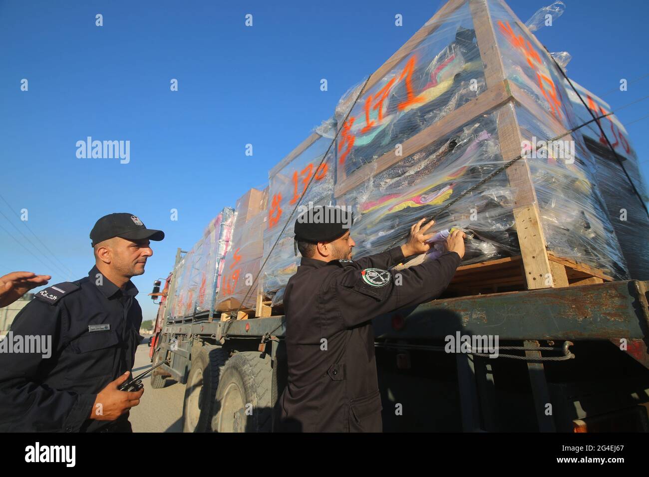 (210621) -- RAFAH, June 21, 2021 (Xinhua) -- A Palestinian police officer inspects clothes for export on a truck at the Kerem Shalom Crossing in the southern Gaza Strip city of Rafah, on June 21, 2021. Israel on Monday eased some restrictions imposed on the Gaza Strip crossings. (Photo by Khaled Omar/Xinhua) Stock Photo