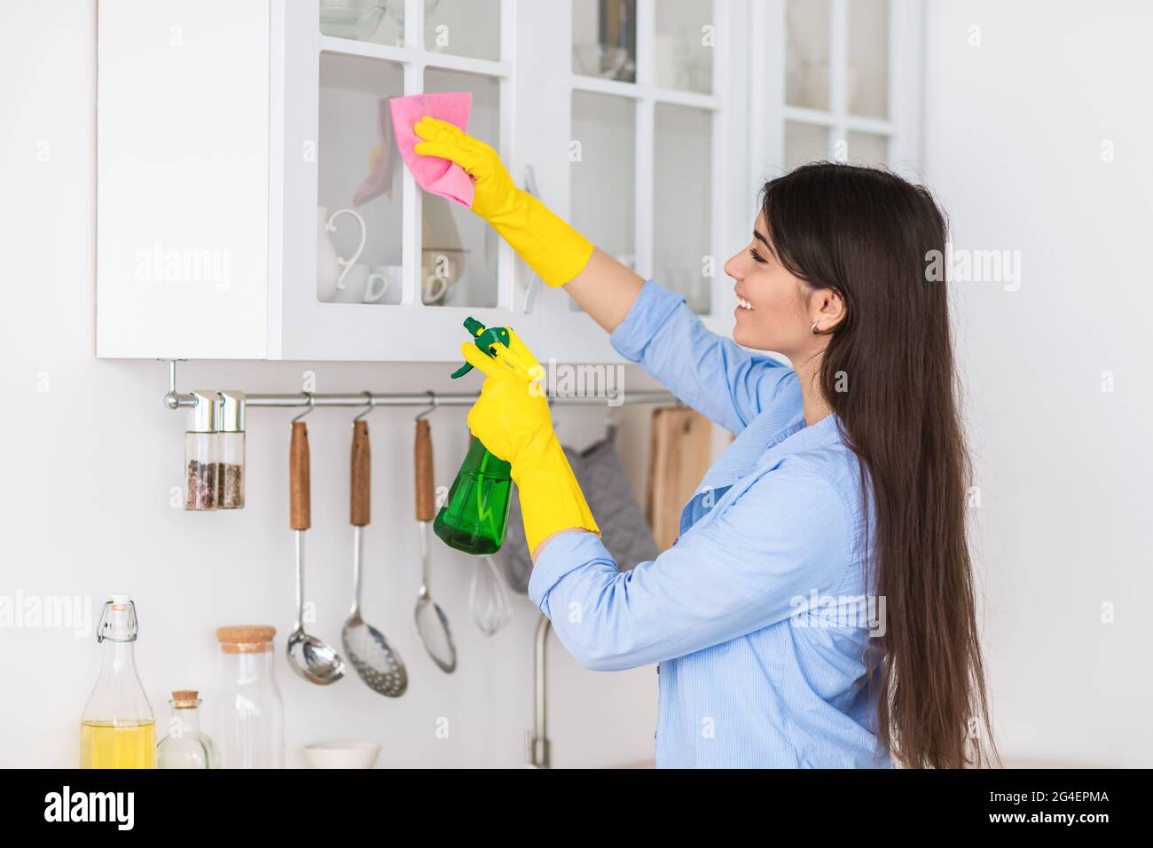 Muslim young woman cleaning shelfs at home at kitchen Stock Photo