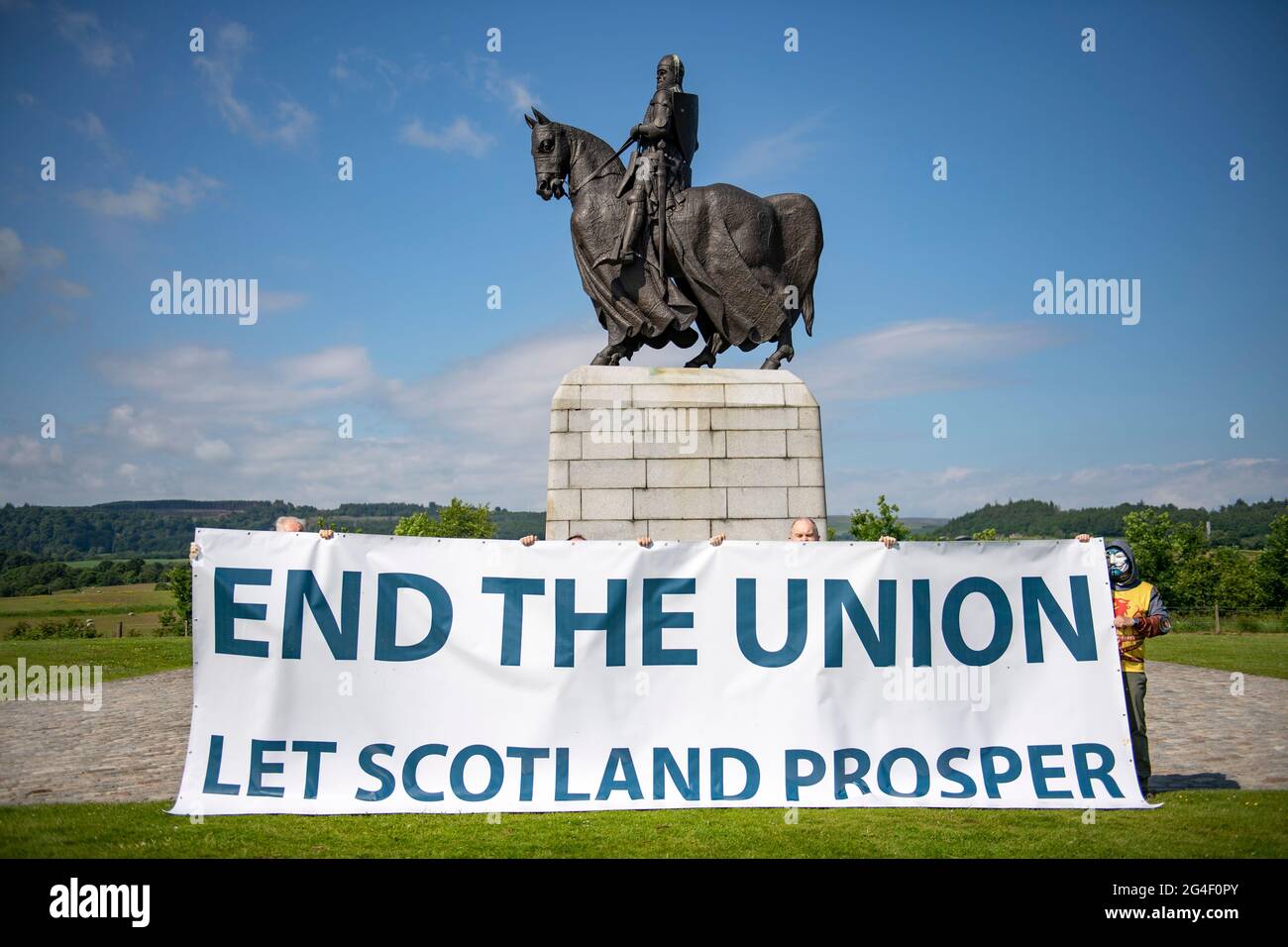 Battle of Bannockburn site, Stirling, Scotland, UK. 21st June, 2021. PICTURED: Sean Clerkin of Action for Scotland, (seen wearing black T-shirt) seen with fellow protestors at the site of the Battle of Bannockburn in front of the Robert the Bruce statue with a large protest banner which reads, ‘END THE UNION LET SCOTLAND PROSPER' in large capital letters. Pic Credit: Colin Fisher/Alamy Live News Stock Photo