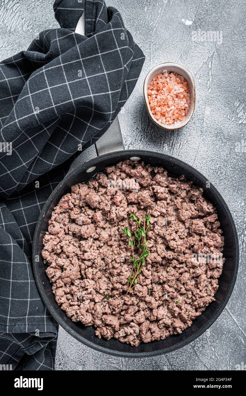 Fried ground mince beef and pork meat in a pan with herbs. White