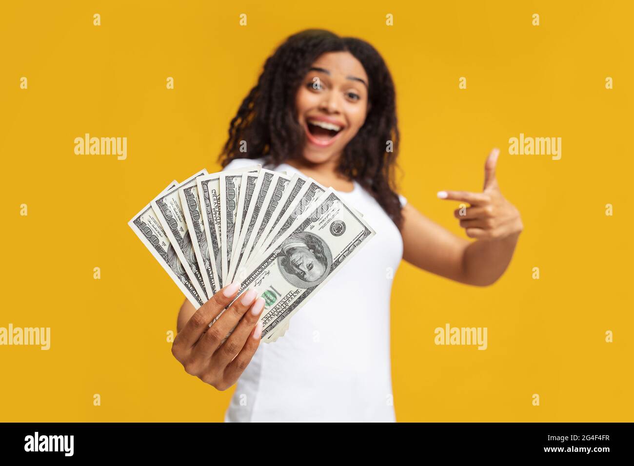 Giveaway concept. Excited young black woman holding a lot of dollar