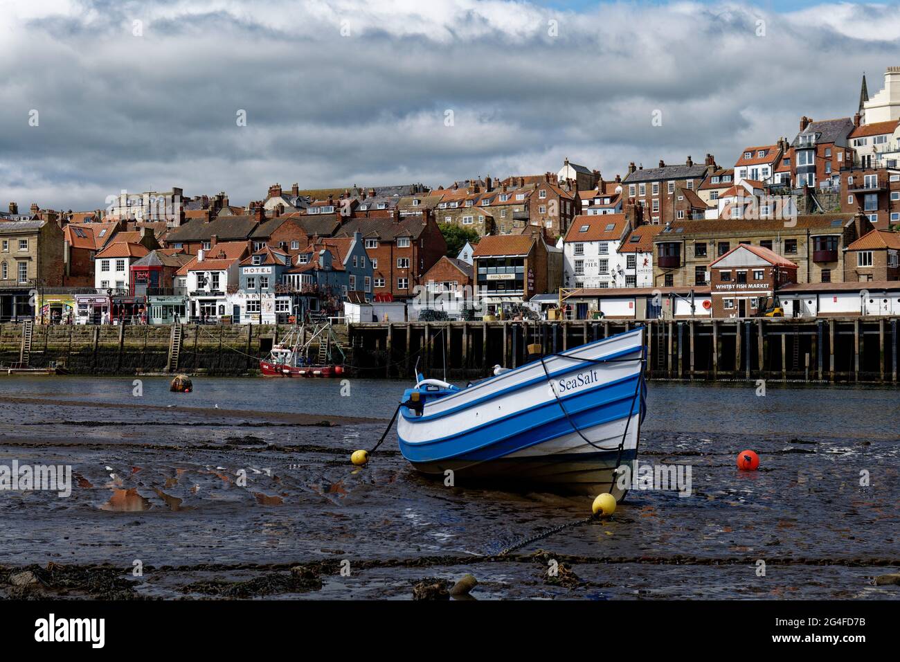 Lovely blue and white  traditional wooden fishing boat sitting on the bed of the river Esk in Whitby Harbour on the North East coast of England Stock Photo