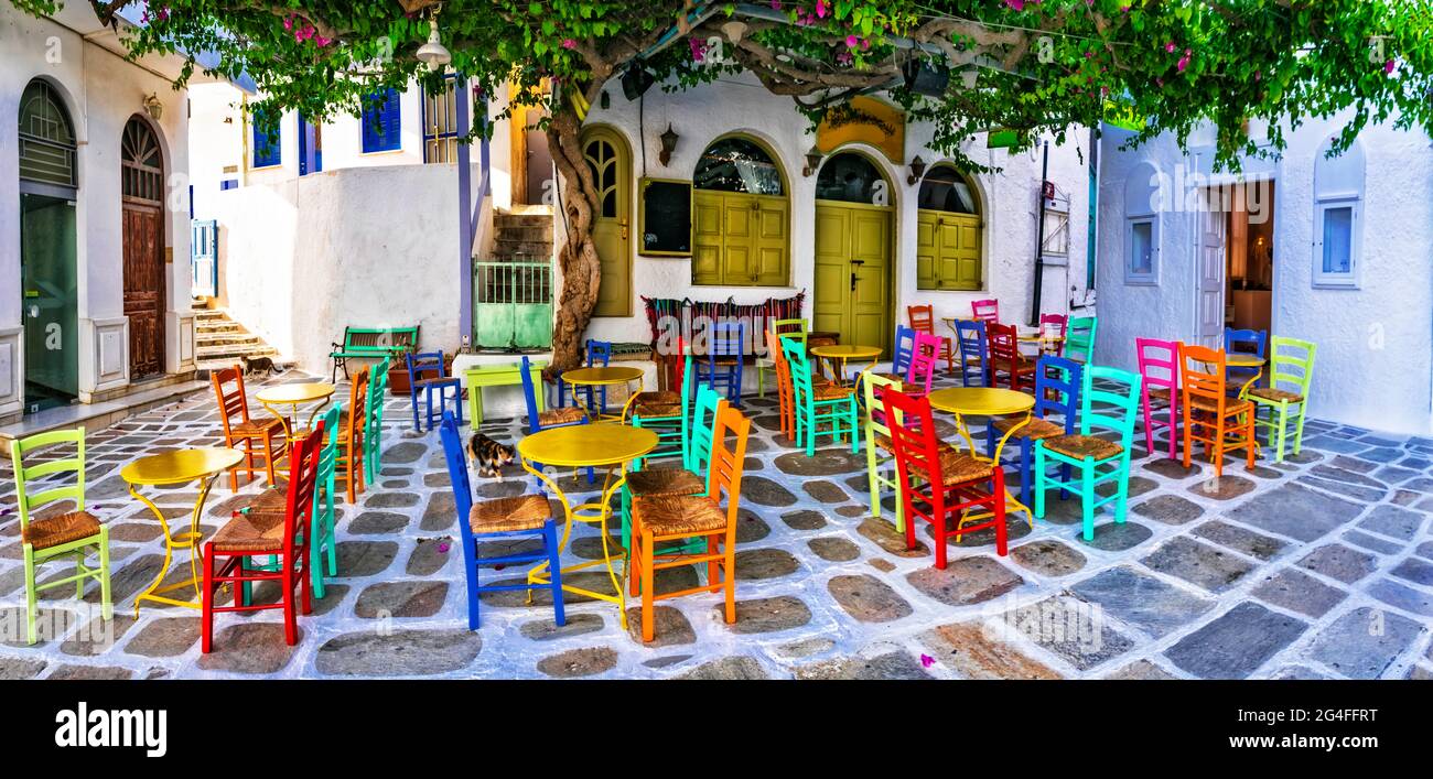 Traditional Greek taverns on the streets. Ios island, old town Chora. Restaurant with colorful typical chairs. Cyclades, Greece Stock Photo