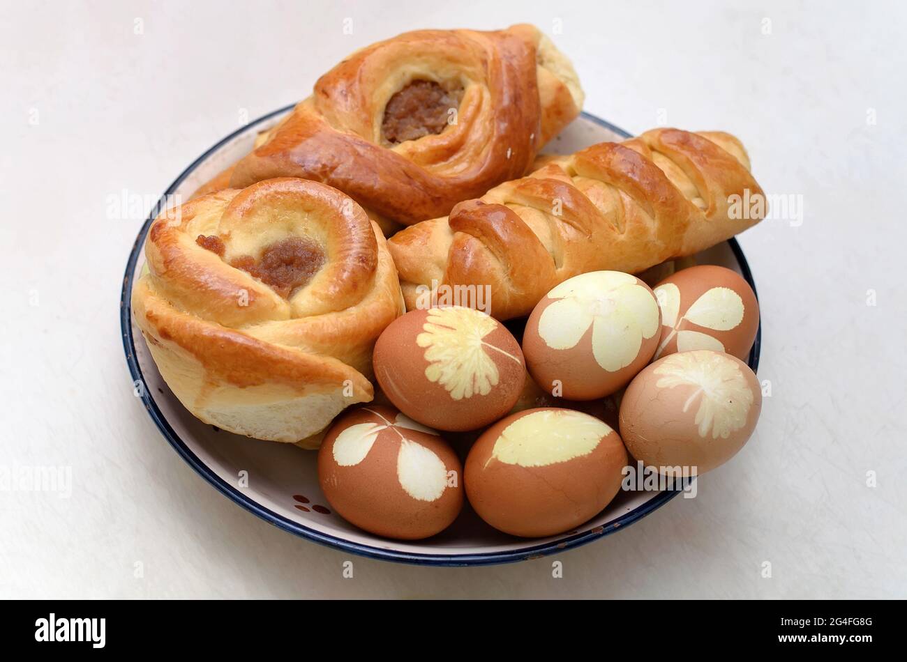 Rich sweet buns with jam and easter eggs with leaf patterns on the plate Stock Photo