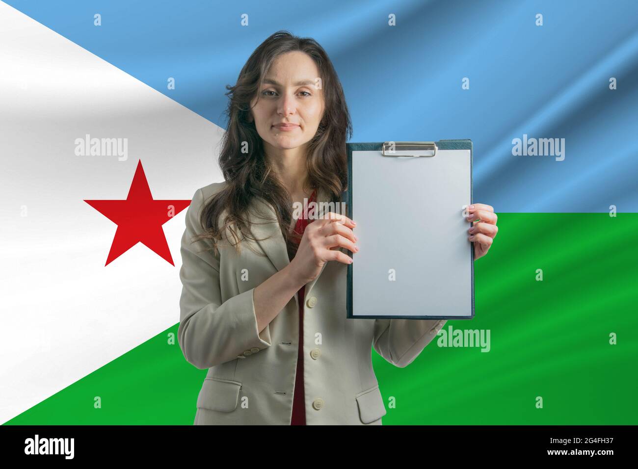 Study in Djibouti. Beautiful woman holding a sheet of paper in her hands. Girl on the background of the flag of Djibouti. Stock Photo