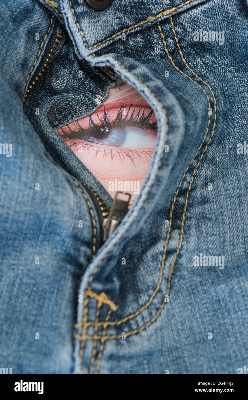 female eye behind the open zipper of denim trousers Stock Photo