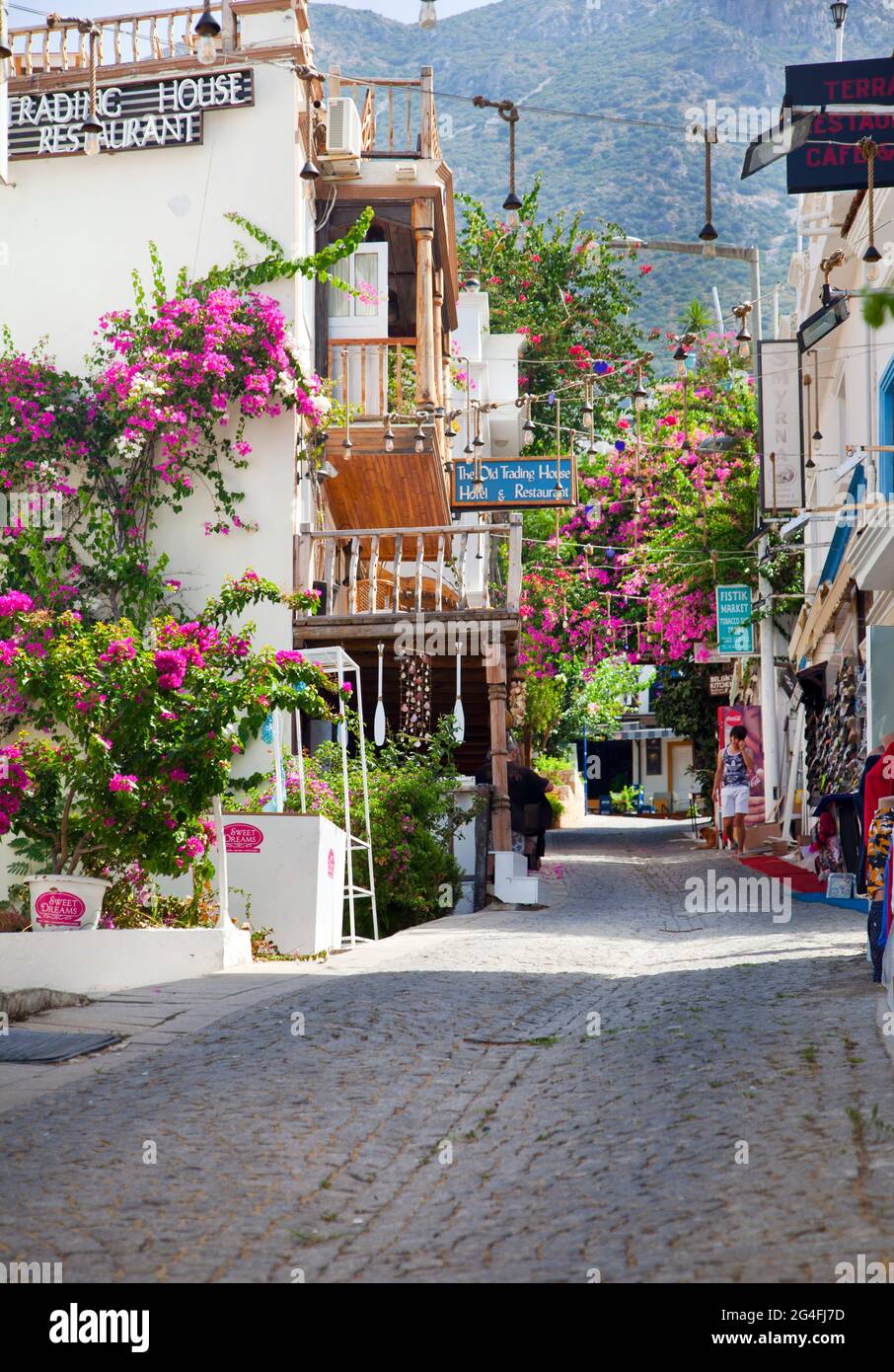 A narrow cobbled street in Kalkan, Turkey, with overhanging balconies coverd in Bougainvillea.  Kalkan is a popular holiday destination and is located Stock Photo
