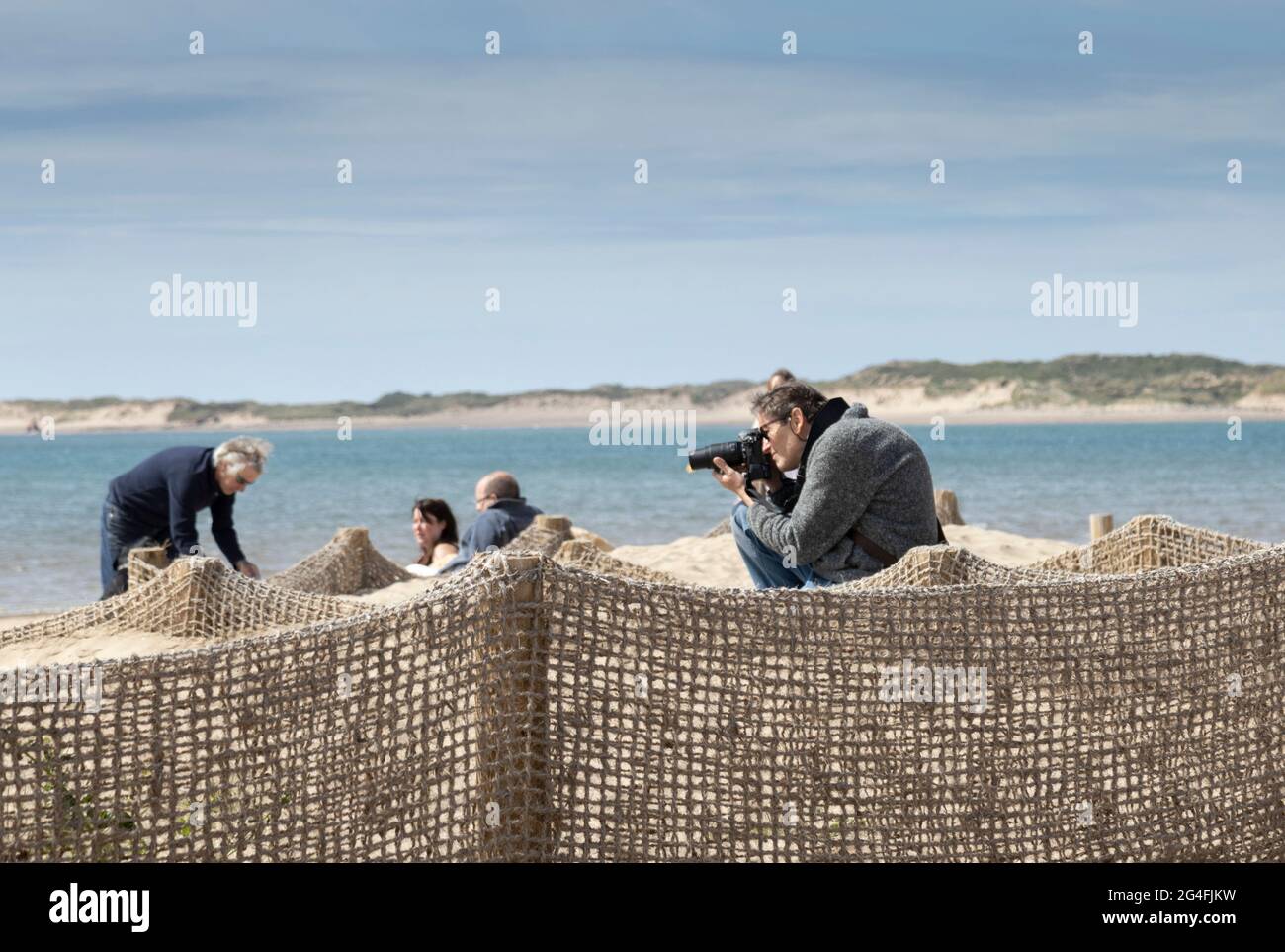 A keen photographer taking photographs on a beach Stock Photo