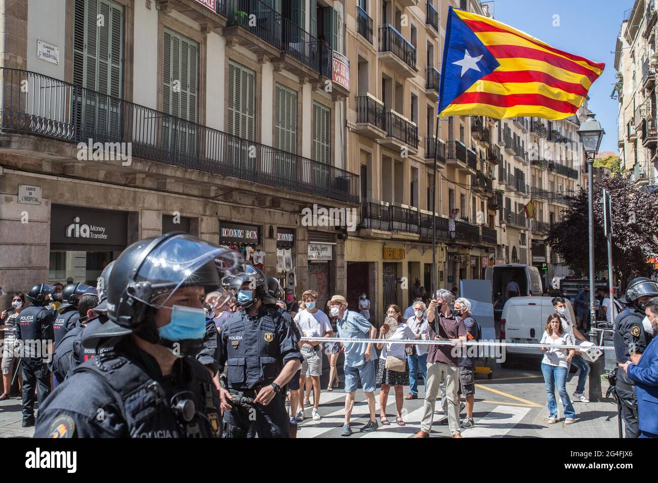 June 21, 2021, Barcelona, Catalonia, Spain: Protester is seen with the Catalan independence flag behind the police.Hundreds of Catalan independentistas have demonstrated this Monday, June 21, in Las Ramblas in Barcelona, in front of the Gran Teatre del Liceu (Great Theater of the Lyceum), shielded by many policemen, to protest the visit of the President of the Spanish Government, Pedro Sanchez, who has held a conference entitled ''Reunion: a project for the future for all of Spain'', with the expectation of an imminent granting of pardons for the independence leaders in prison. The protesters Stock Photo