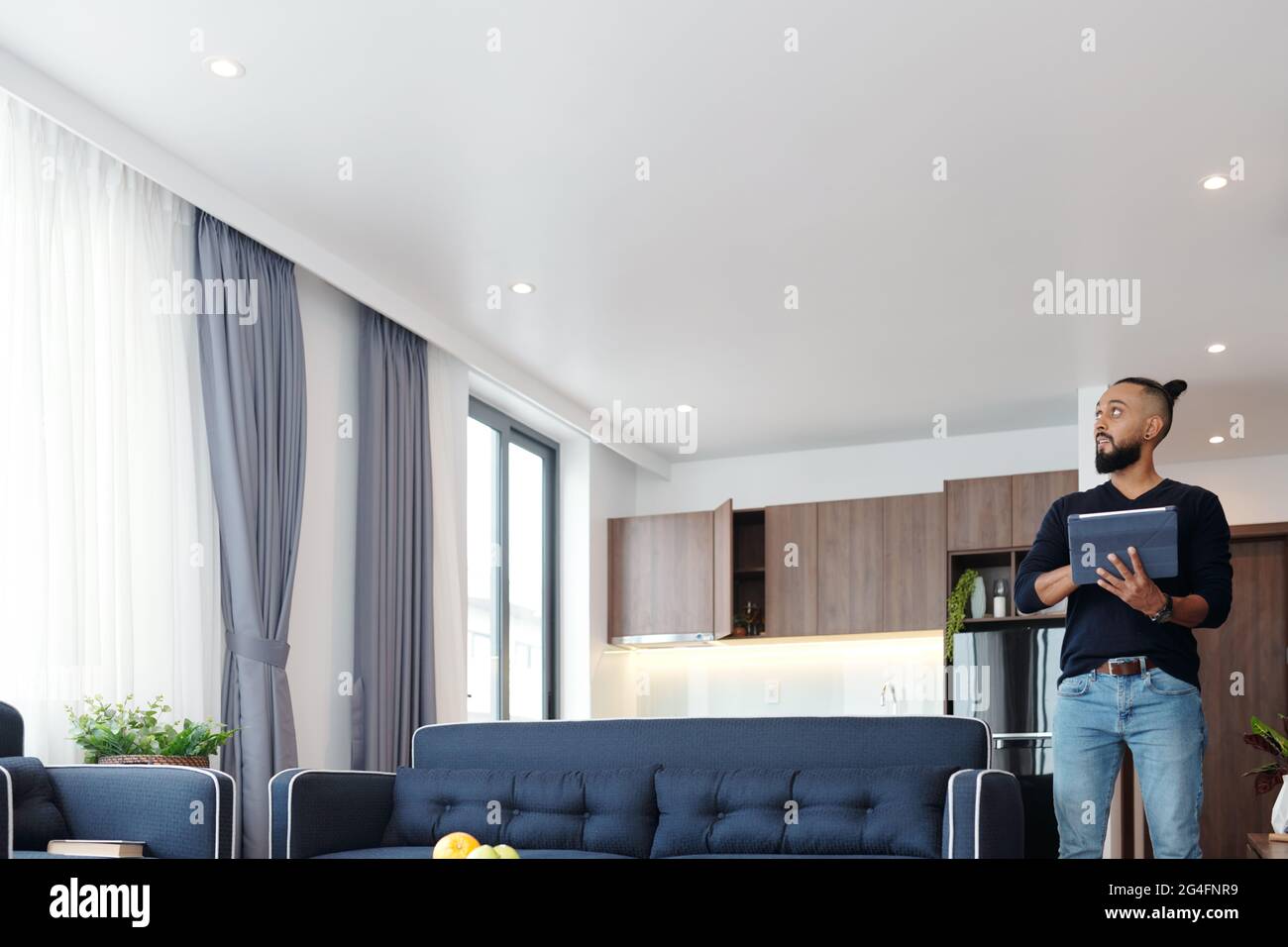 Bearded man using application on tablet computer when controlling light and temperature in his apartment Stock Photo