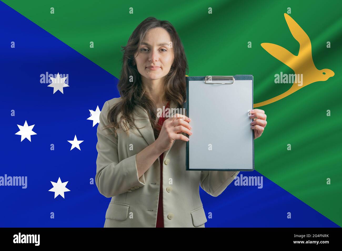 Study in Christmas Island. Beautiful woman holding a sheet of paper in her hands. Girl on the background of the flag of Christmas Island. Stock Photo