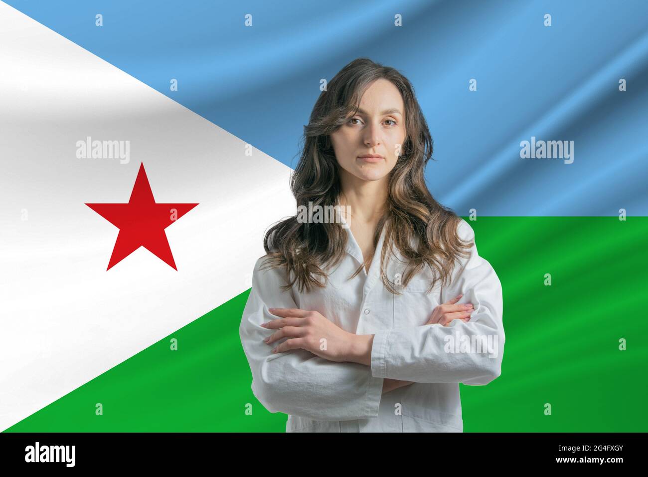Medicine in Djibouti. Happy beautiful female doctor in medical coat standing with crossed arms against the background of the flag of Djibouti. Stock Photo