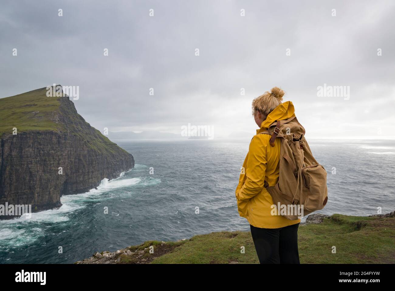 A women contemplating the sea along the Traelanipa walking trail by lake Sorvagsvatn on the island of Vagar in the Faroe Islands Stock Photo