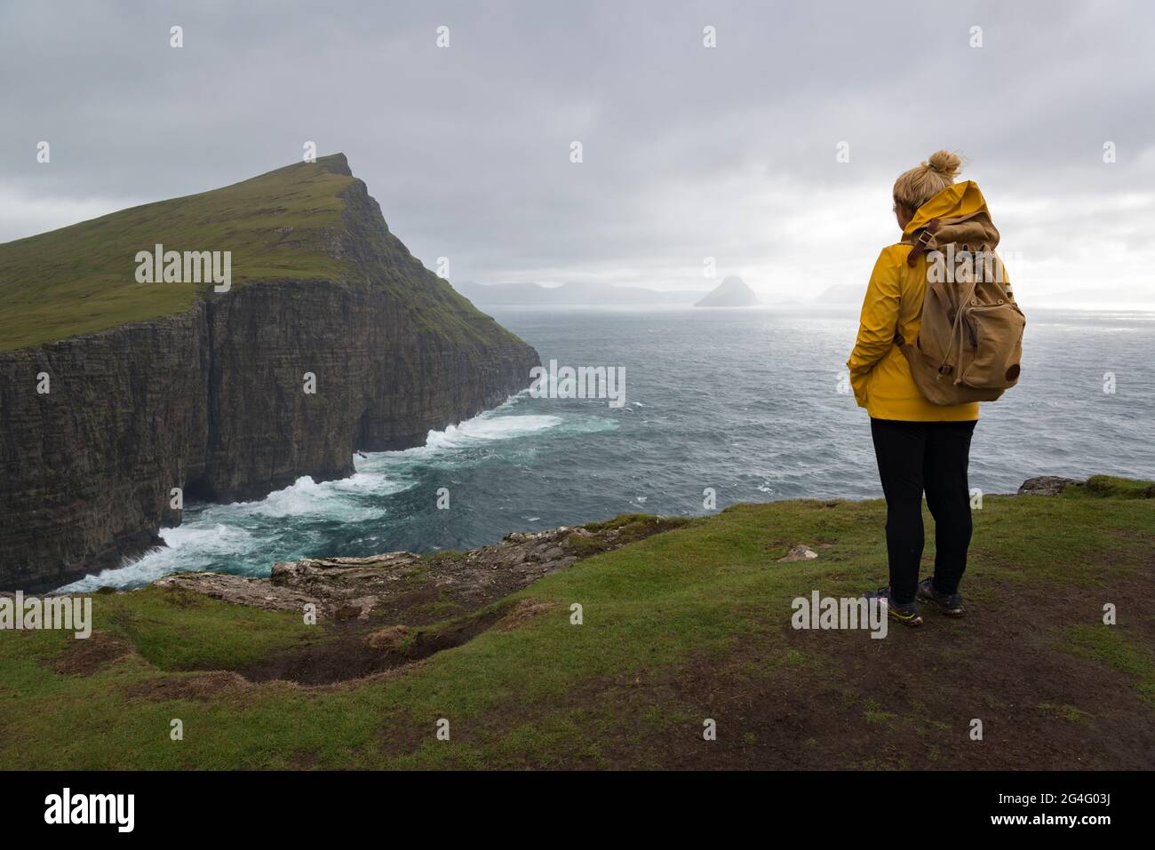 A women contemplating the sea along the Traelanipa walking trail by lake Sorvagsvatn on the island of Vagar in the Faroe Islands Stock Photo