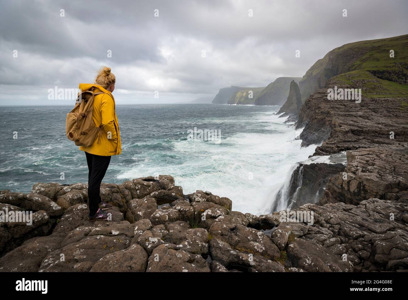 A women contemplating the sea along the Traelanipa walking trail by lake Sorvagsvatn on the island of Vagar in the Faroe Islands Stock Photo