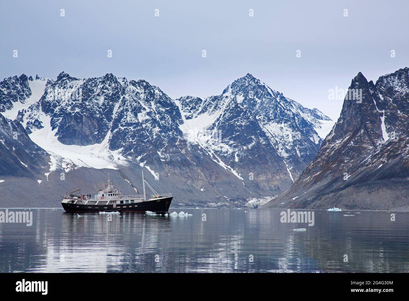 Expedition vessel / expedition yacht MV Togo and jagged mountains along Magdalenefjorden, Albert I Land, Svalbard / Spitsbergen, Norway Stock Photo
