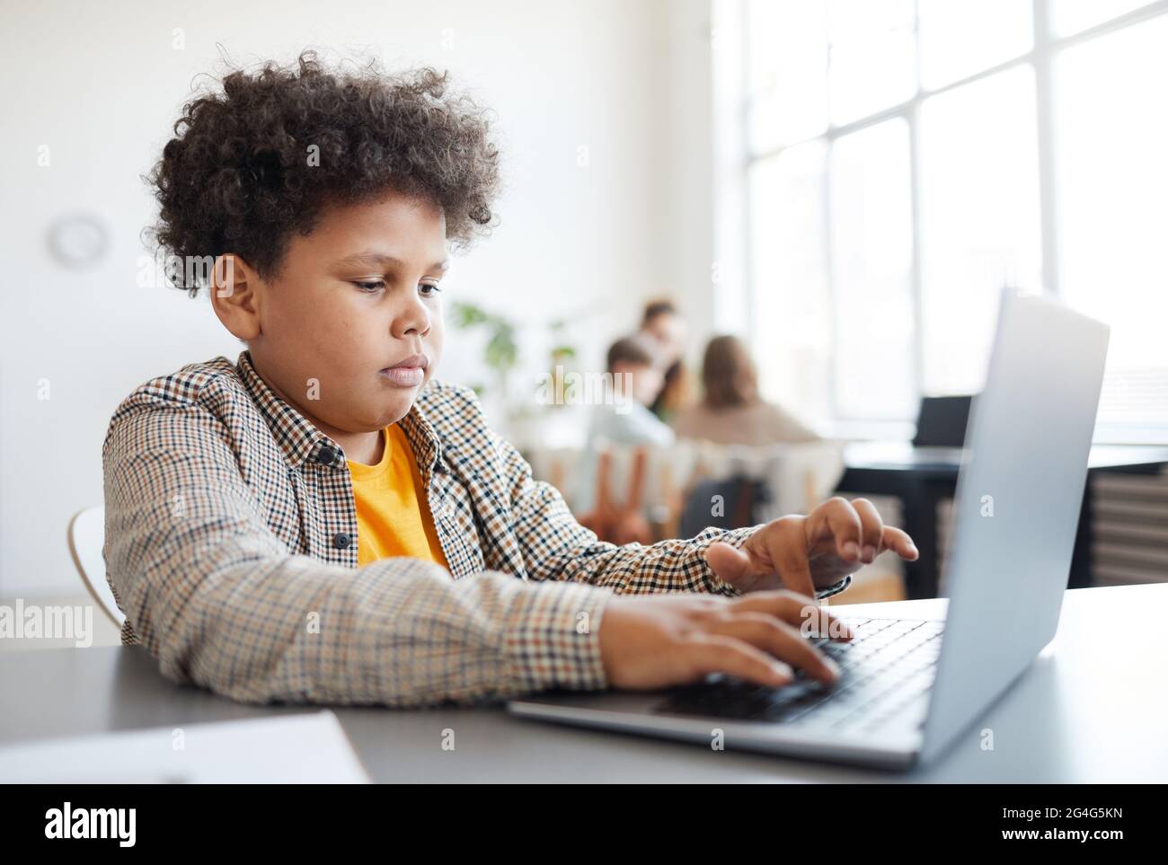 Side view portrait of African-American schoolboy using laptop in class ...