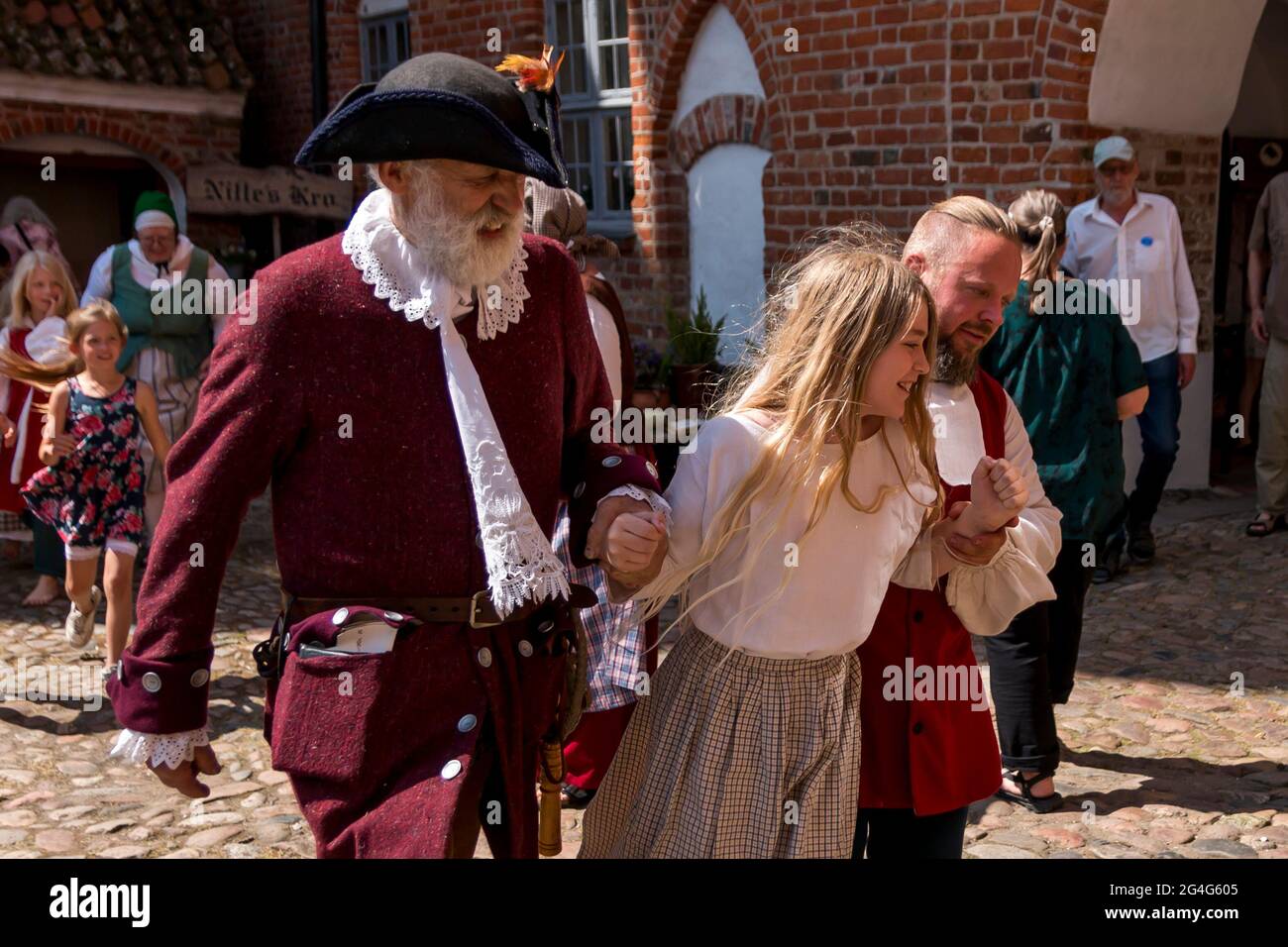 Auning, Denmark - 19 June 2021: A girl from the 18th century is caught by a bailiff and a man because she has stolen pancakes Stock Photo