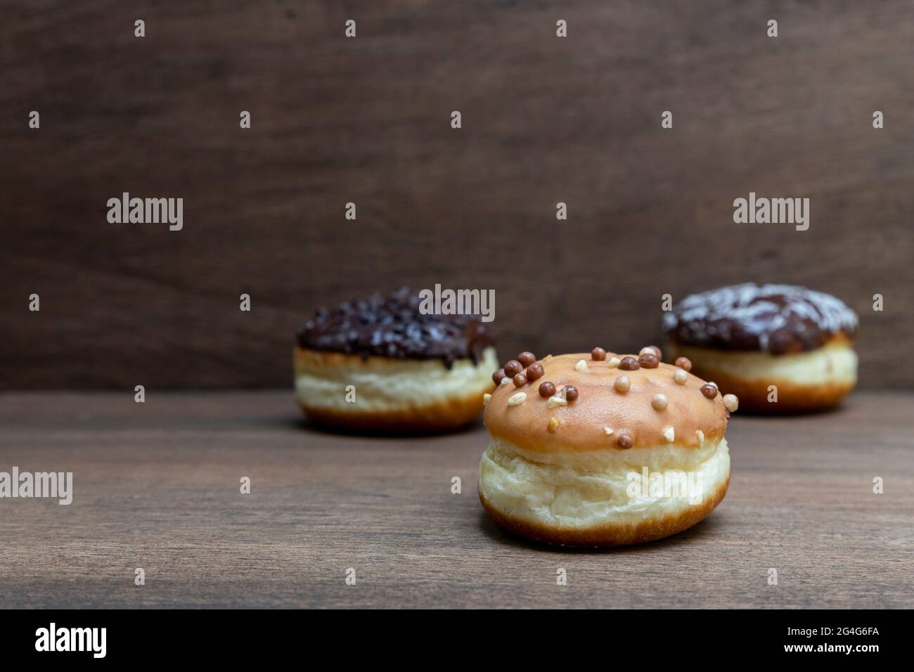 Delicious glazed chocolate donuts on wooden background Stock Photo - Alamy